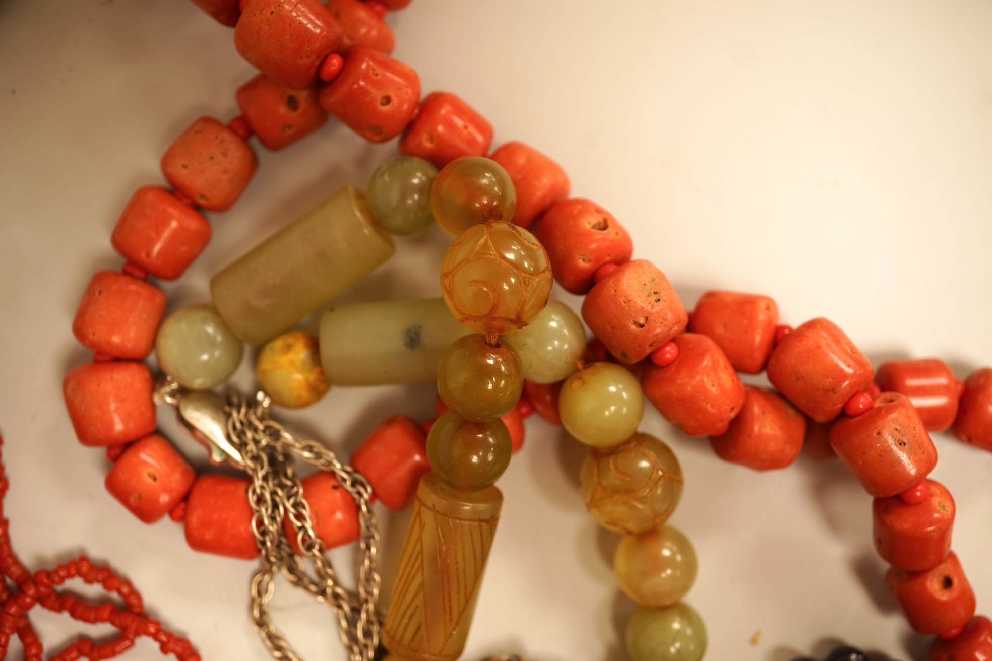A small group of sundry jewellery including a simulated amber necklace and a multi strand coral bead necklace, etc.